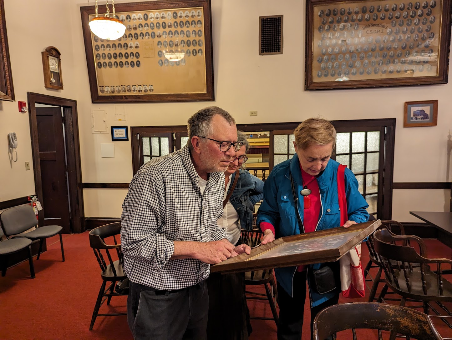 A small group examining an framed photo collection. 